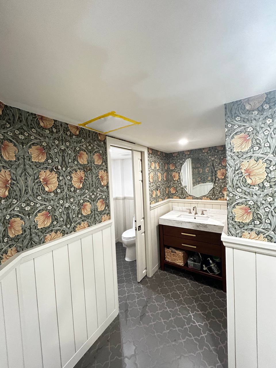 Close-up view of skilled workers smoothing out a large artistic abstract mural wallpaper on a feature wall to ensure a wrinkle-free application.
