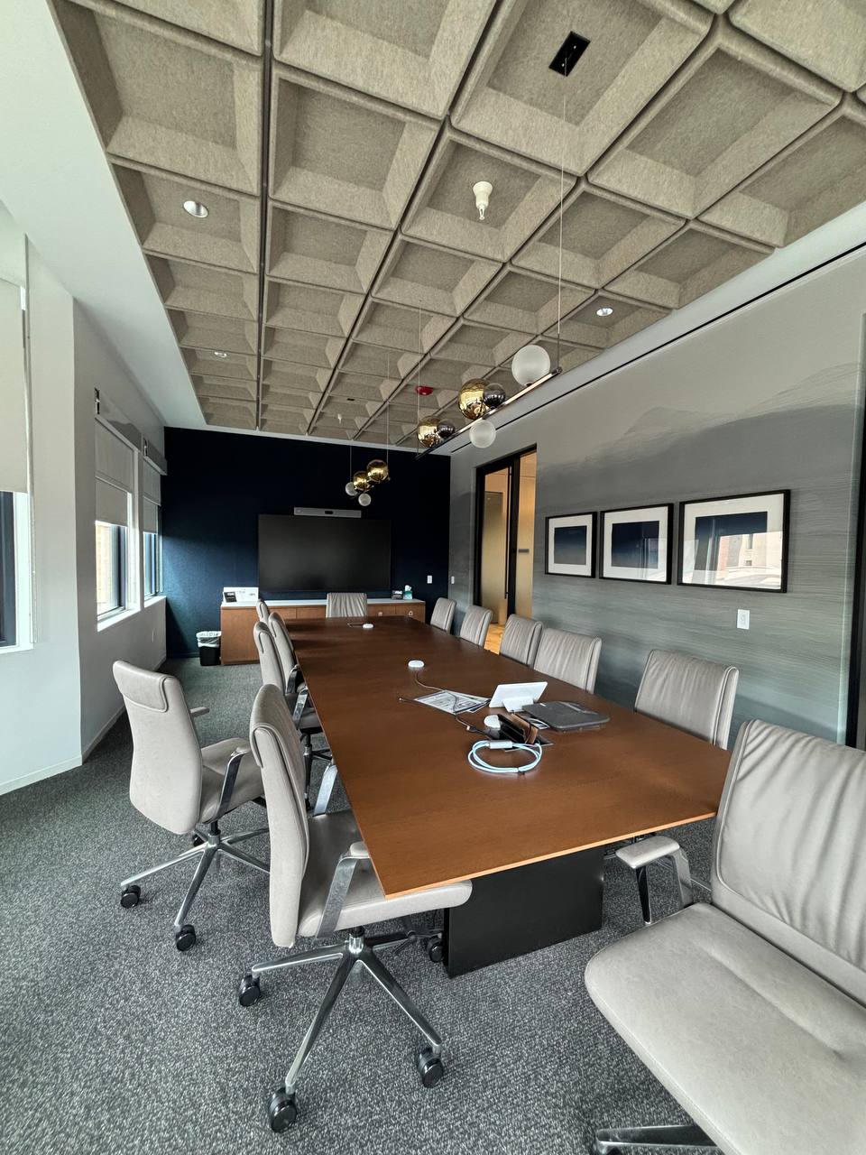 Long residential corridor showcasing light gray wood-grain texture wallcovering installed beneath a row of large windows with hardwood floors.