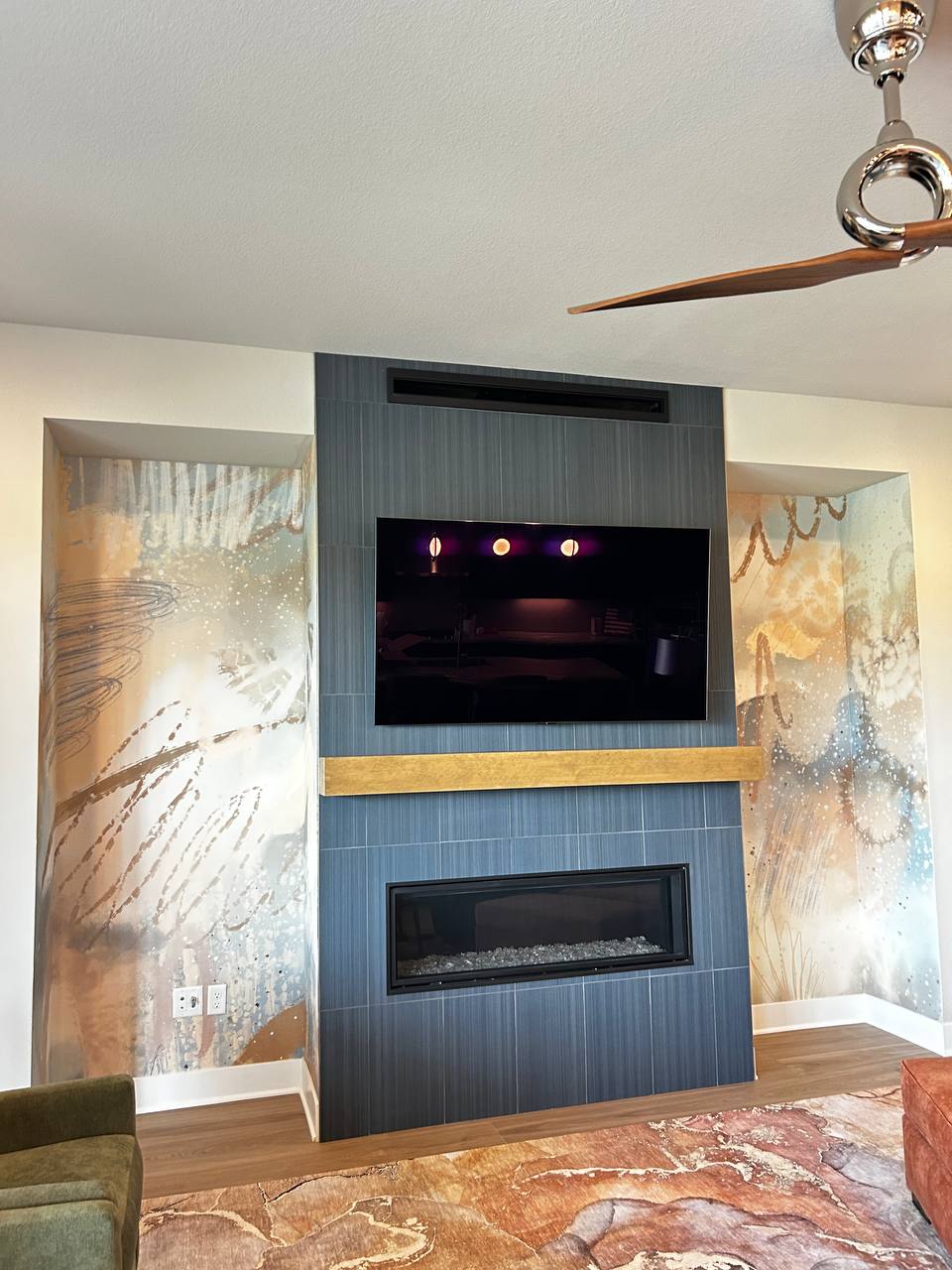 Modern kitchen feature wall displaying a massive custom abstract mural wallpaper with earthy tones and distressed brushstroke textures behind dark cabinetry.
