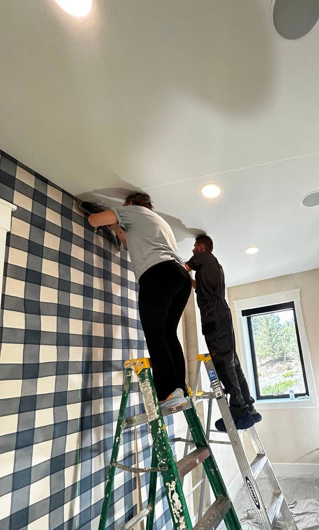 Feature wall behind TV displaying blue vertical slat paneling flanked by textured abstract wallpaper accents in an artistic design.
